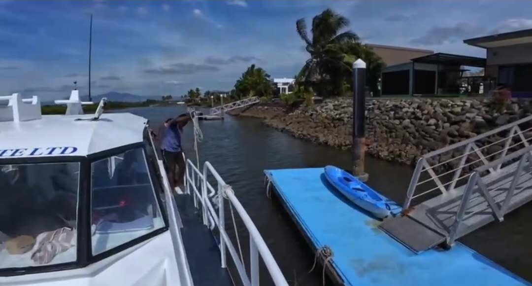 A boat pulling up alongside the dock, kayak waiting on the pontoon
