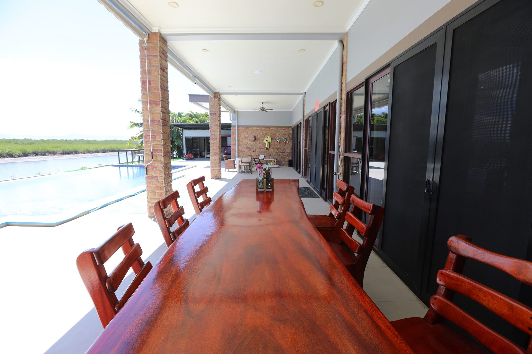 The long timber dining table beside the pool