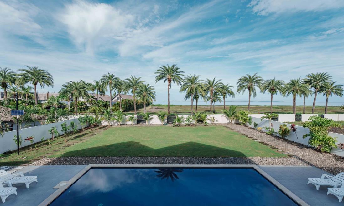 Villa 102's garden and pool looking out toward the sea beyond the fence line